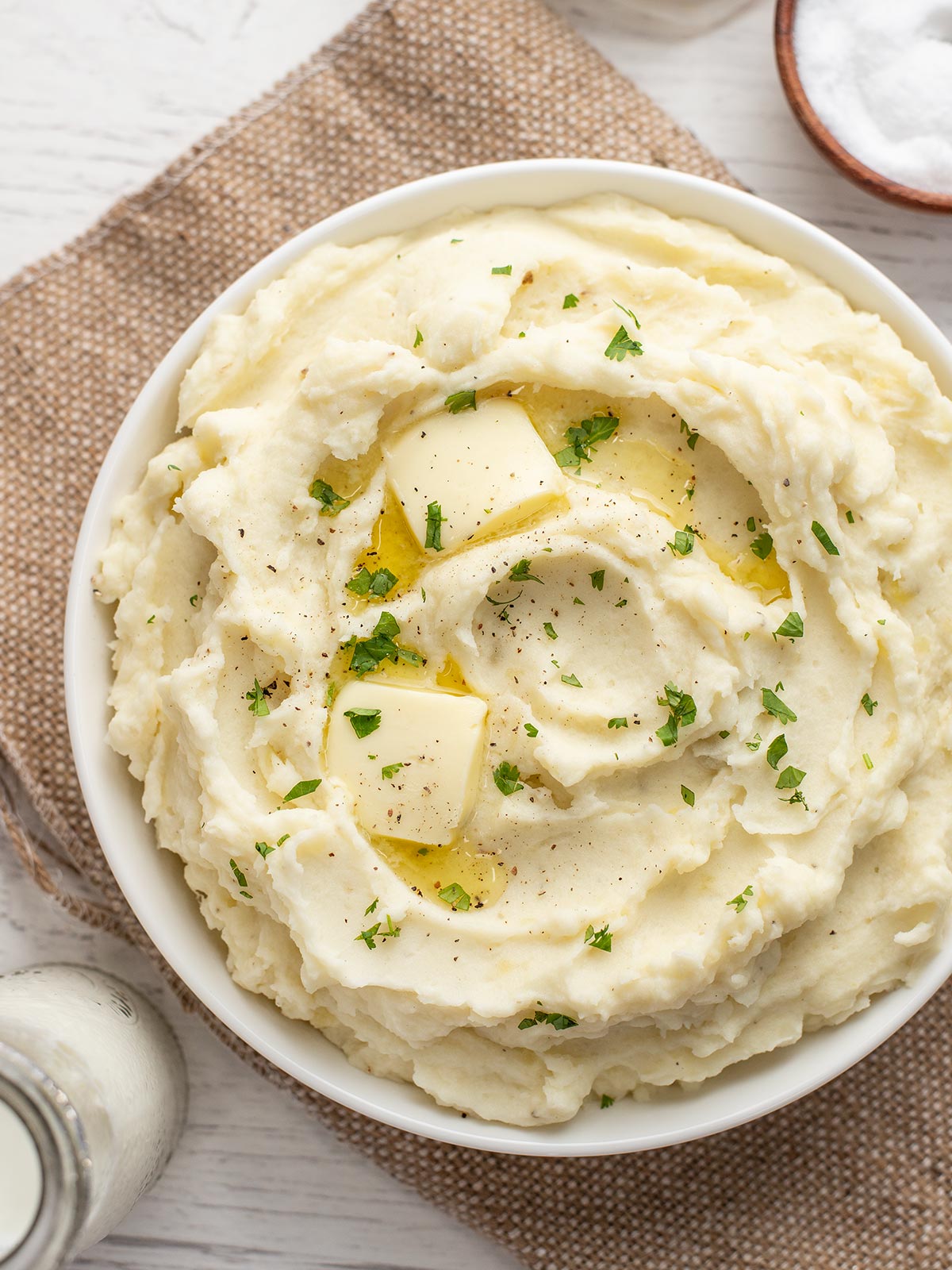 Overhead view of a bowl of mashed potatoes with melted butter.
