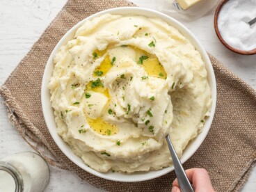 Mashed potatoes being scooped out of a bowl.