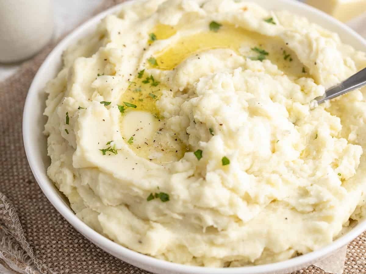 Close up side view of a bowl of mashed potatoes with melted butter.
