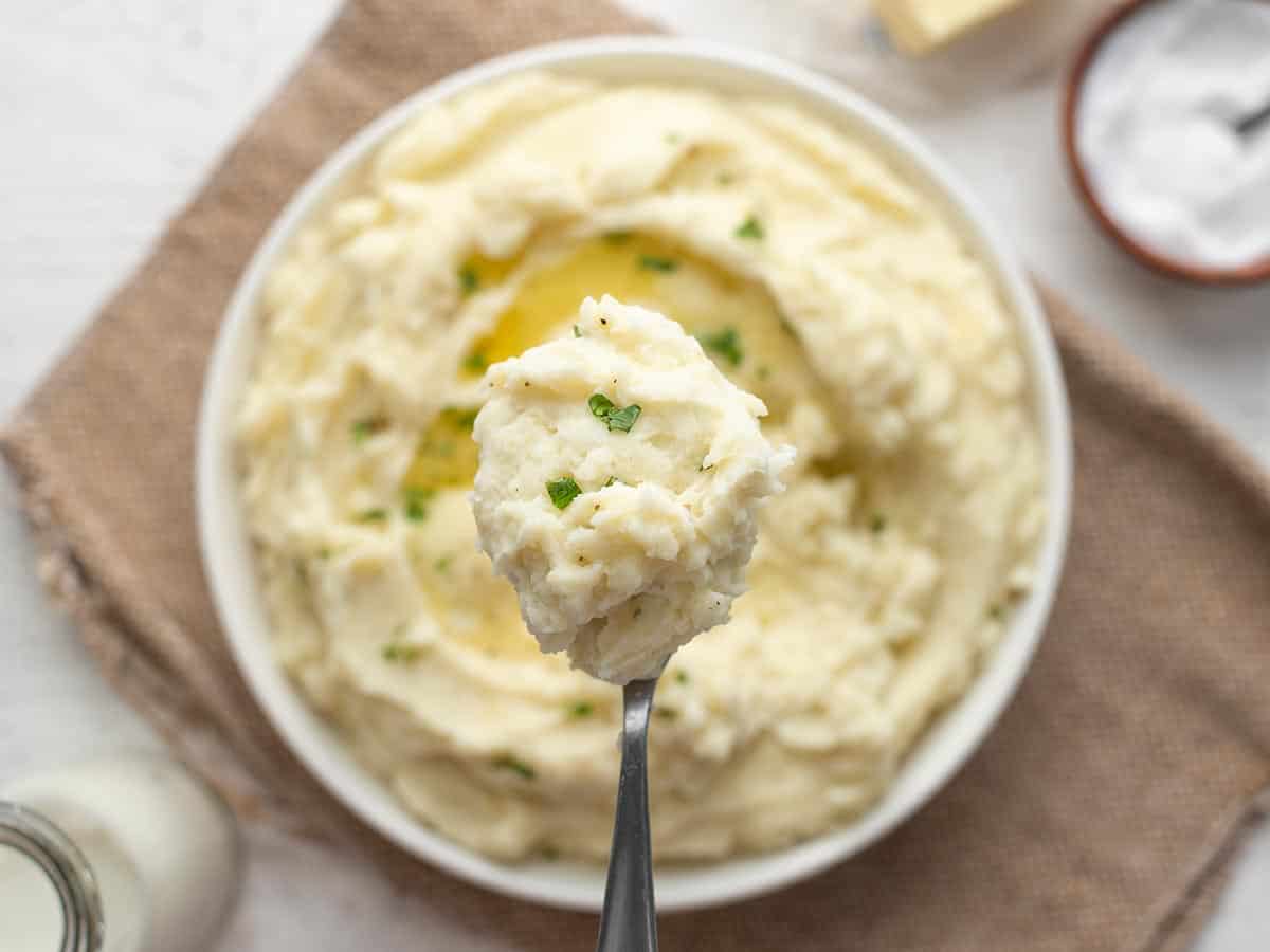 Close up view of a scoop of mashed potatoes on a spoon.
