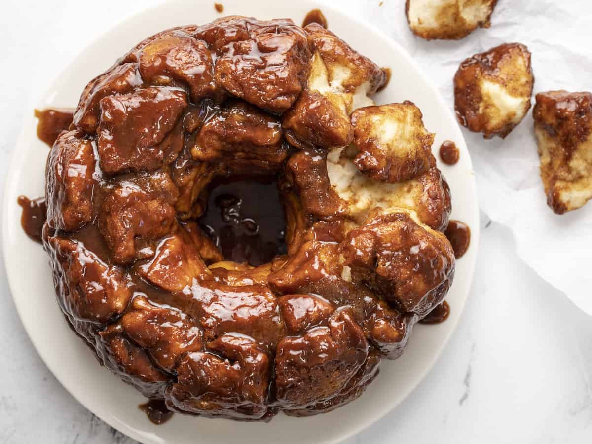 Overhead shot of monkey bread on white plate with a few pieces picked out of it .