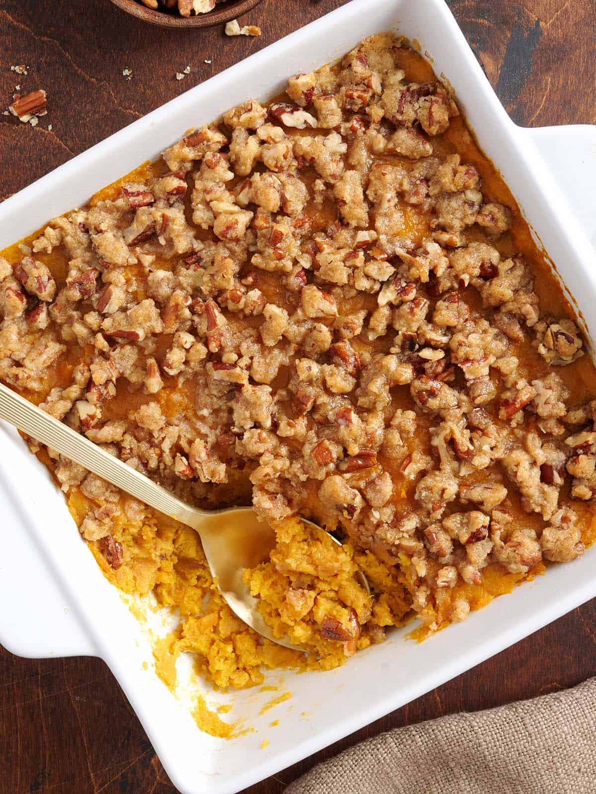 Overhead view of pecan sweet potato casserole in baking dish with a spoon.