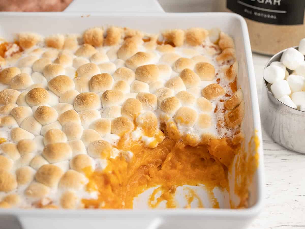 Overhead shot of a sweet potato casserole in a white casserole dish with a few scoops taken out of it.