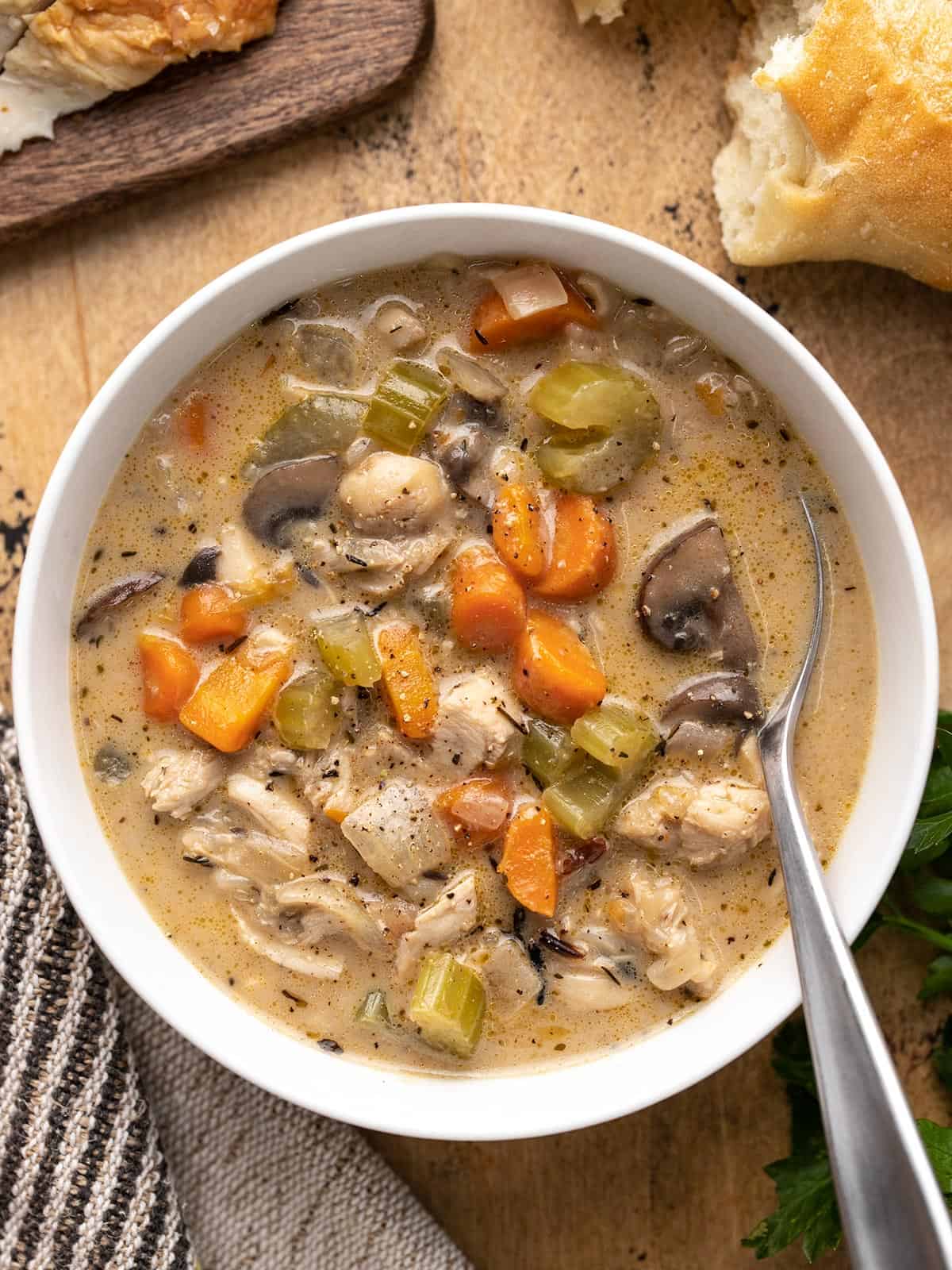 Overhead view of a bowl of turkey and wild rice soup on a wood surface.