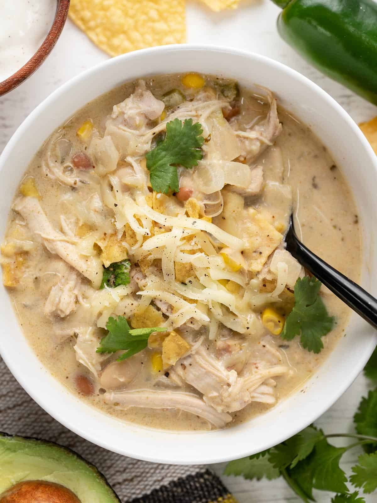 close up overhead view of a bowl of white chicken chili with chips and cheese.