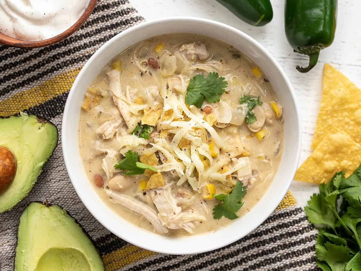 Overhead view of a bowl of white chicken chili with toppings. 