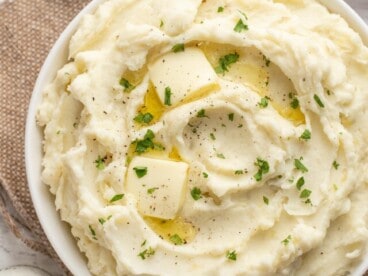 Overhead view of a bowl of mashed potatoes with melted butter.