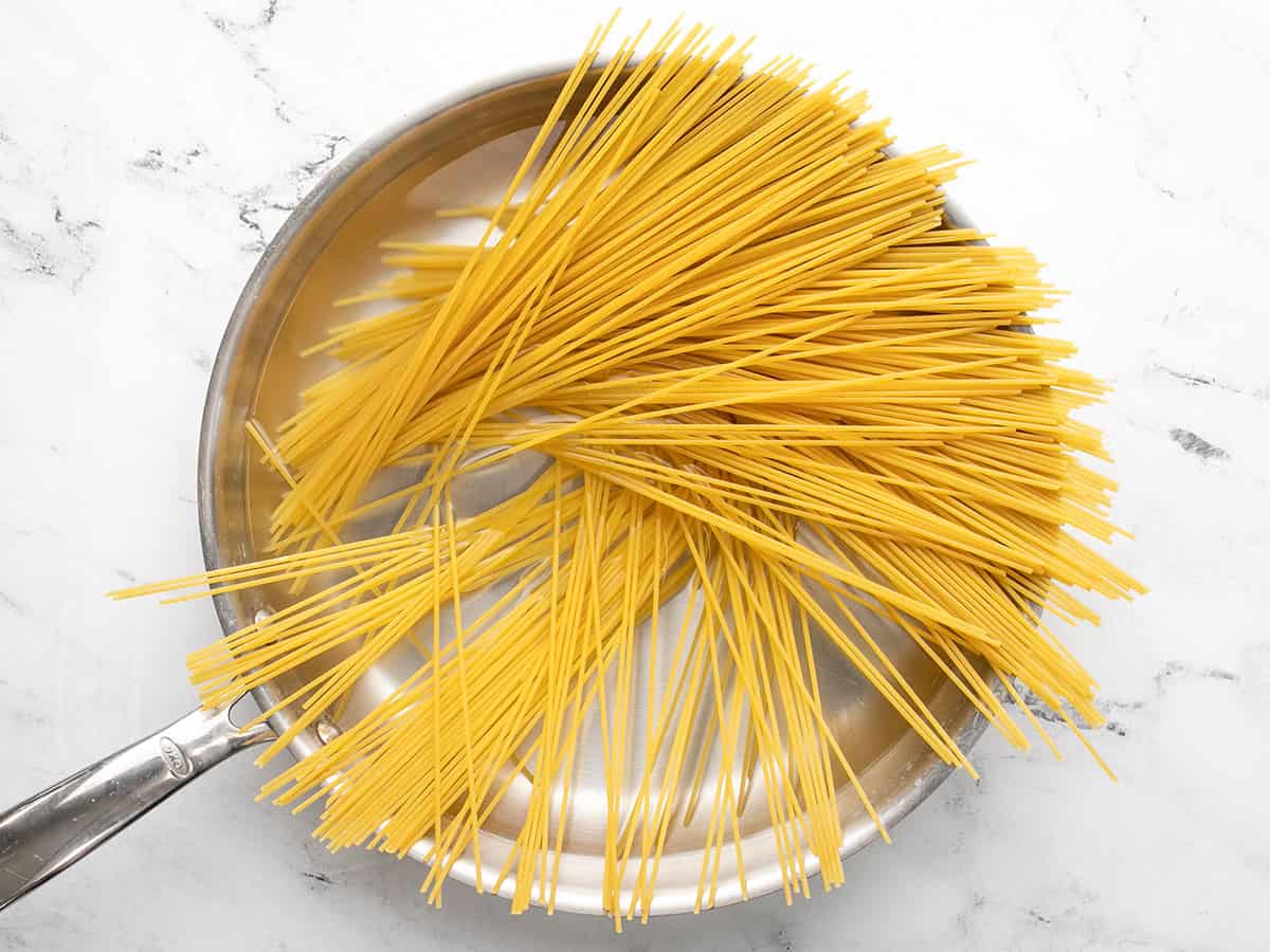 Raw spaghetti in a pan of boiling water.
