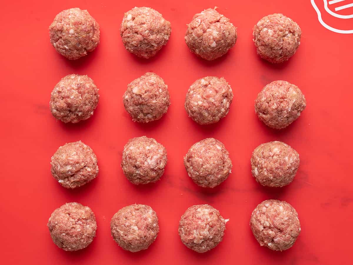 Shaped meatballs on a red cutting board.