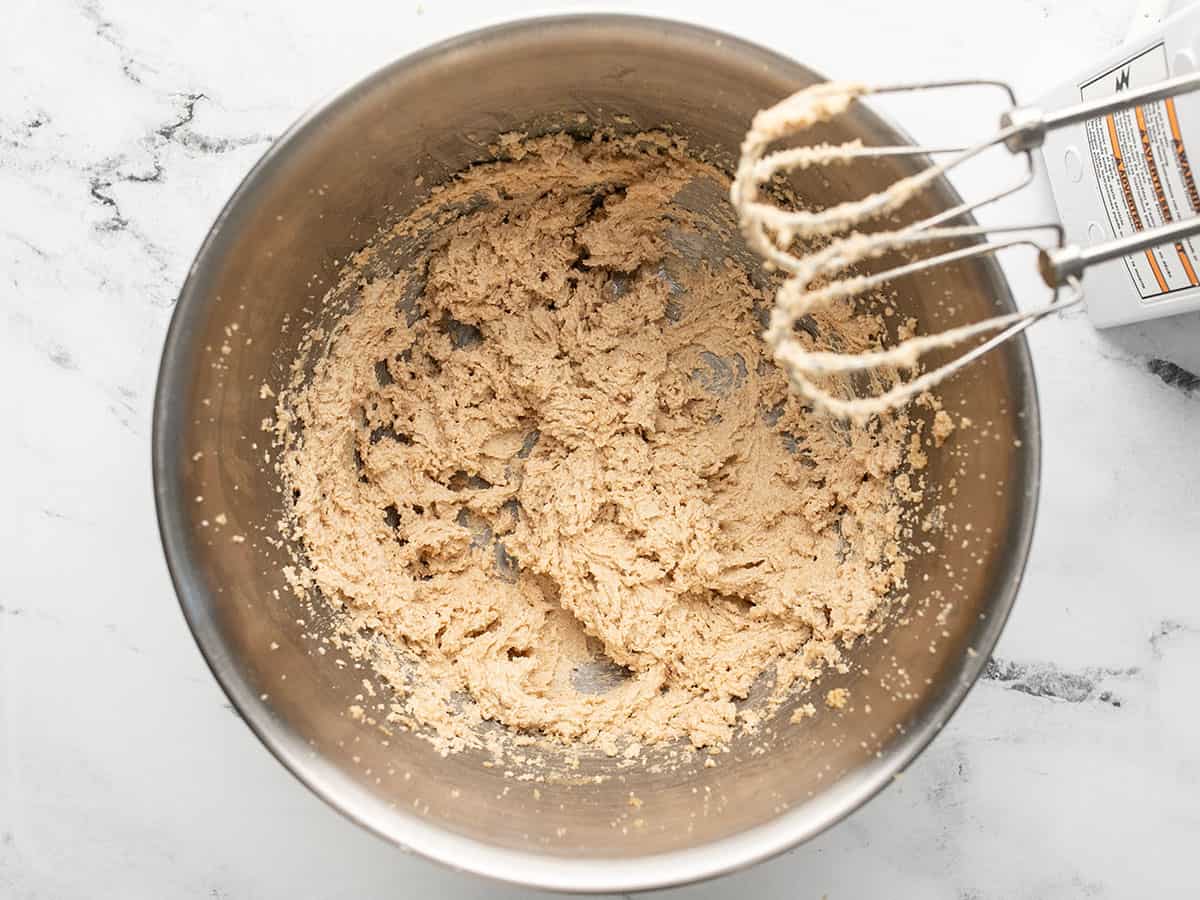 Overhead shot of creamed sugar in a silver bowl with hand beaters settled on the rim..