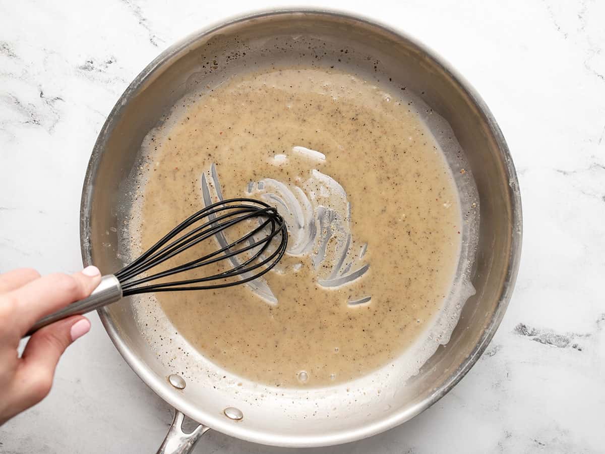 Hand whisking sauce as it reduces.