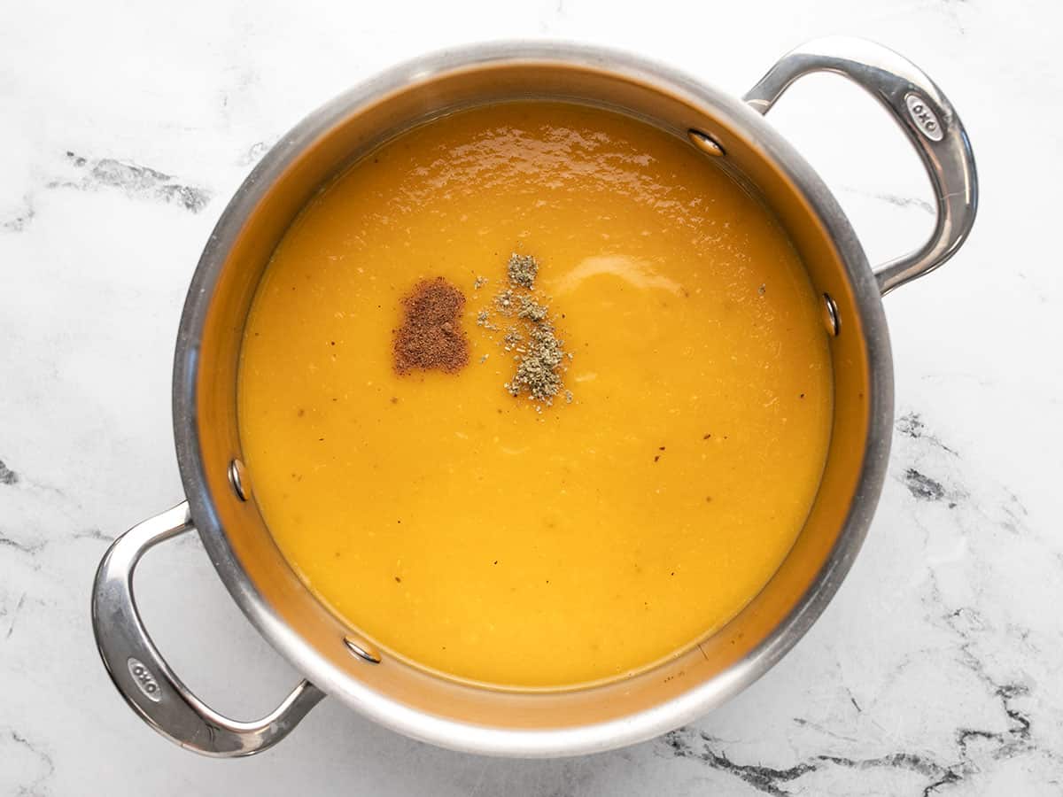 Butternut squash soup in a pot with herbs added. 