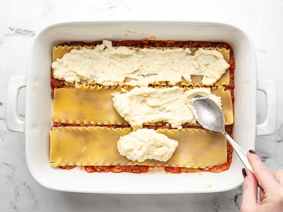 Lasagna being layered into the casserole dish.