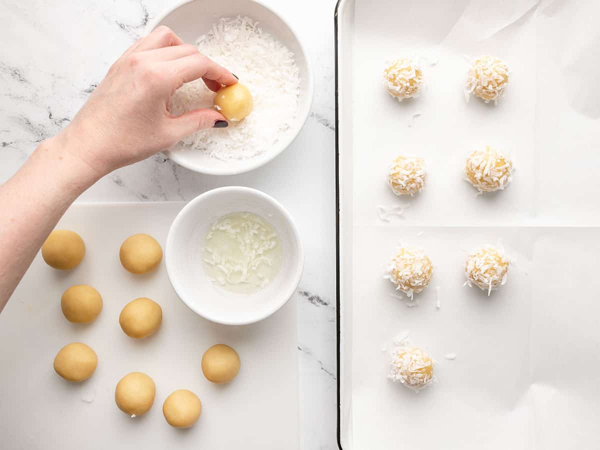 Cookies being dipped in egg white and coconut. 