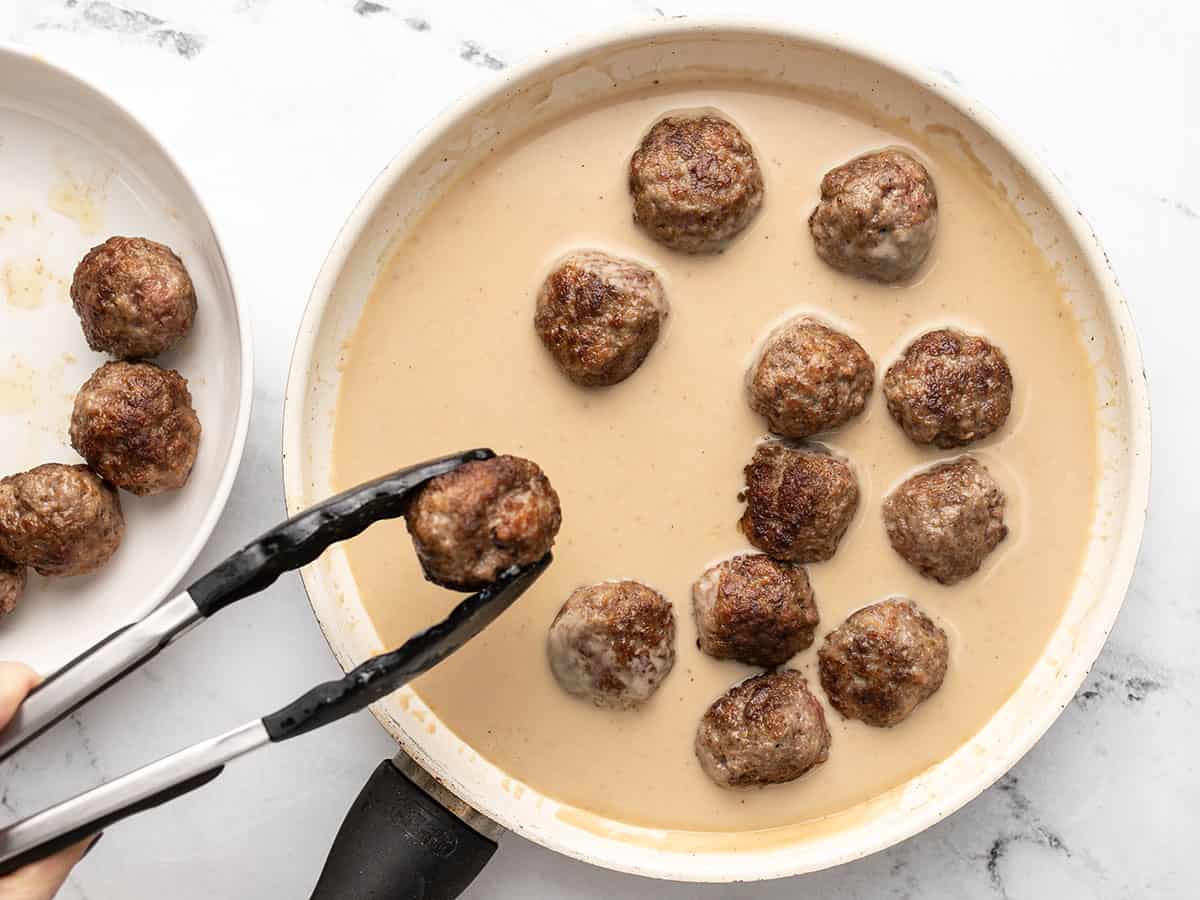 Meatballs being added back to the skillet.