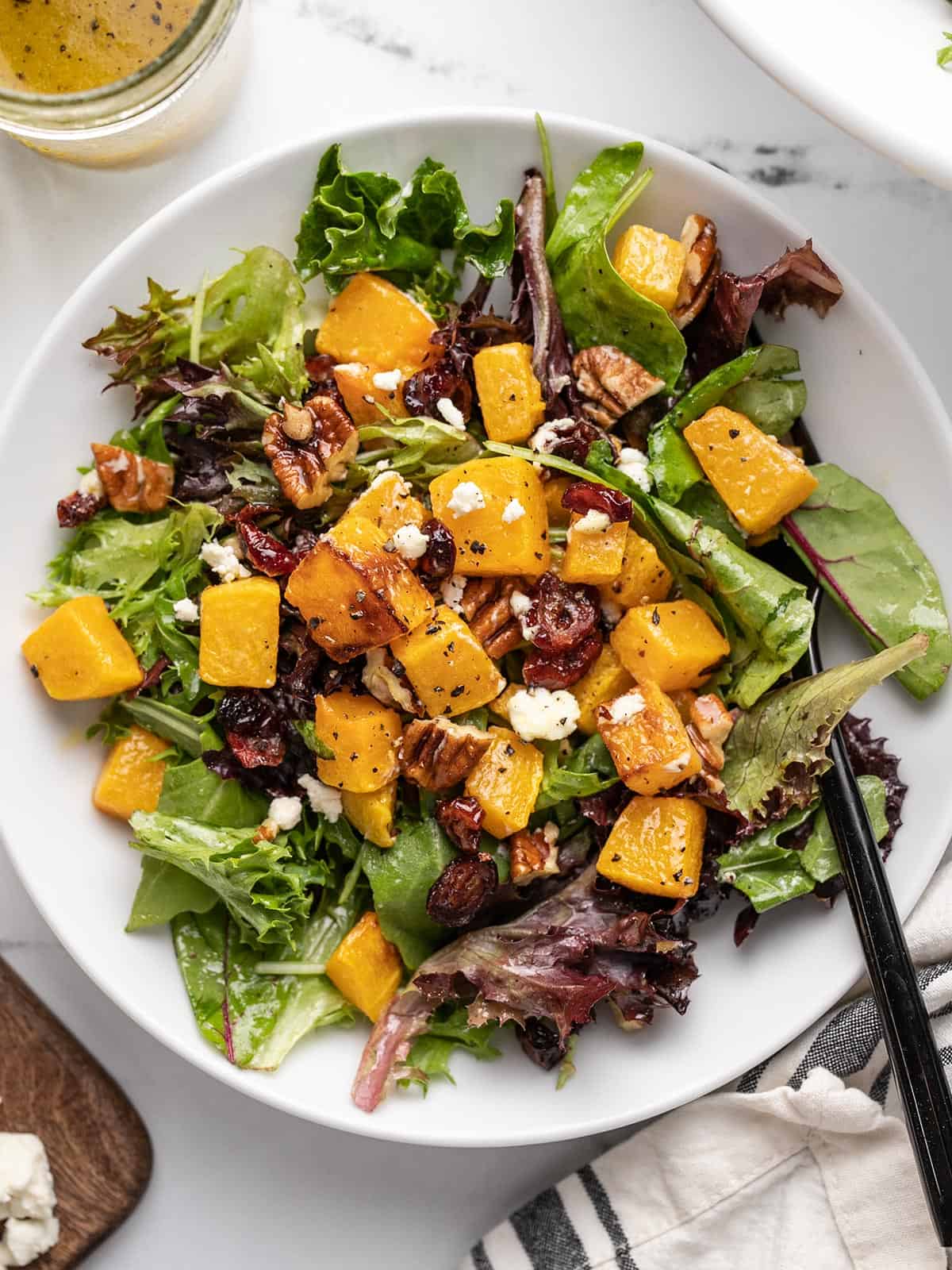 Overhead view of a butternut squash salad in a bowl with a fork.