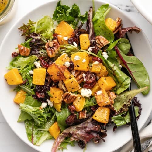 Close up overhead shot of one serving of butternut squash salad in a bowl.