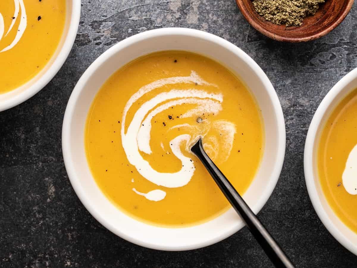 Overhead view of a single bowl full of butternut squash soup with cream swirled on top.