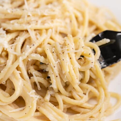 Side shot of finished Cacio e Pepe on a plate with a fork in it.