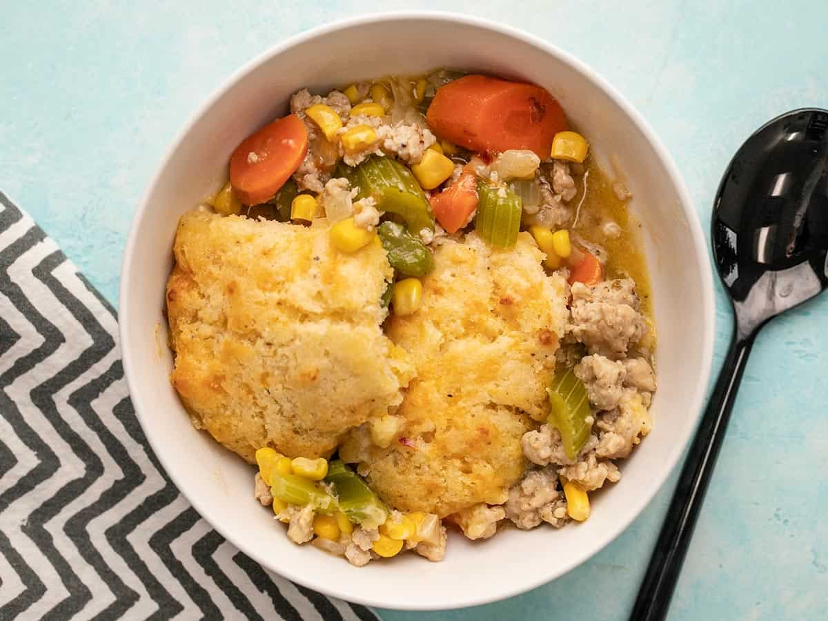 Cooked chicken and biscuit casserole in a serving bowl with a spoon.
