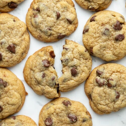 Colpo dall'alto di biscotti con gocce di cioccolato su una teglia con uno dei biscotti strappato a metà.