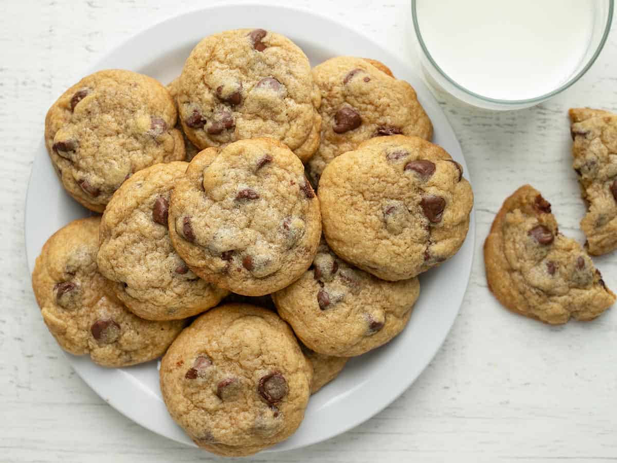 Overhead shot of chocolate chip cookies on a plate with a glass of milk next to it.