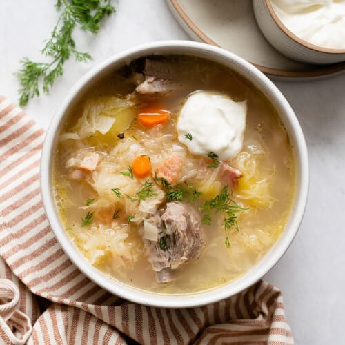 Overhead view of a bowl of kapusniak with sour cream.