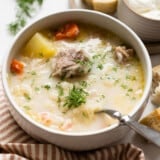 Side view of a bowl of kapusniak with a spoon.