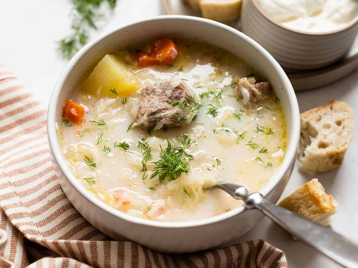 Side view of a bowl of kapusniak with a spoon.