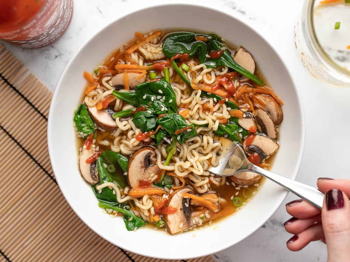 Overhead view of a bowl of noodle soup with sriracha.