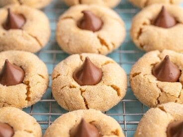 Side view of peanut butter blossoms lined up on a cooling rack.