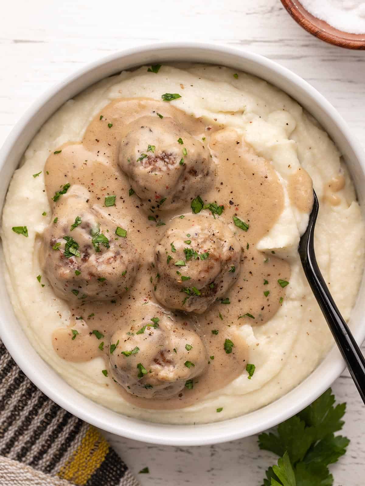 Overhead view of a bowl of mashed potatoes topped with Swedish meatballs.