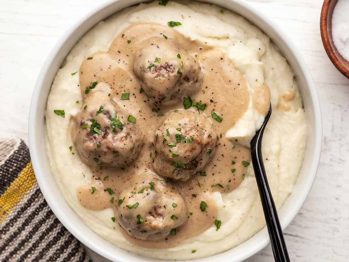 Overhead view of a bowl full of mashed potatoes topped with Swedish meatballs.