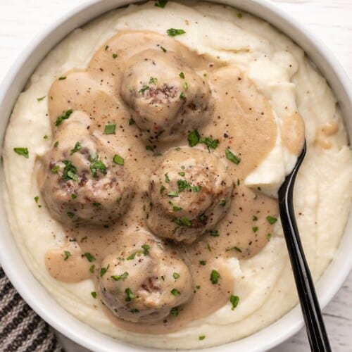 Overhead view of a bowl full of mashed potatoes and Swedish Meatballs.