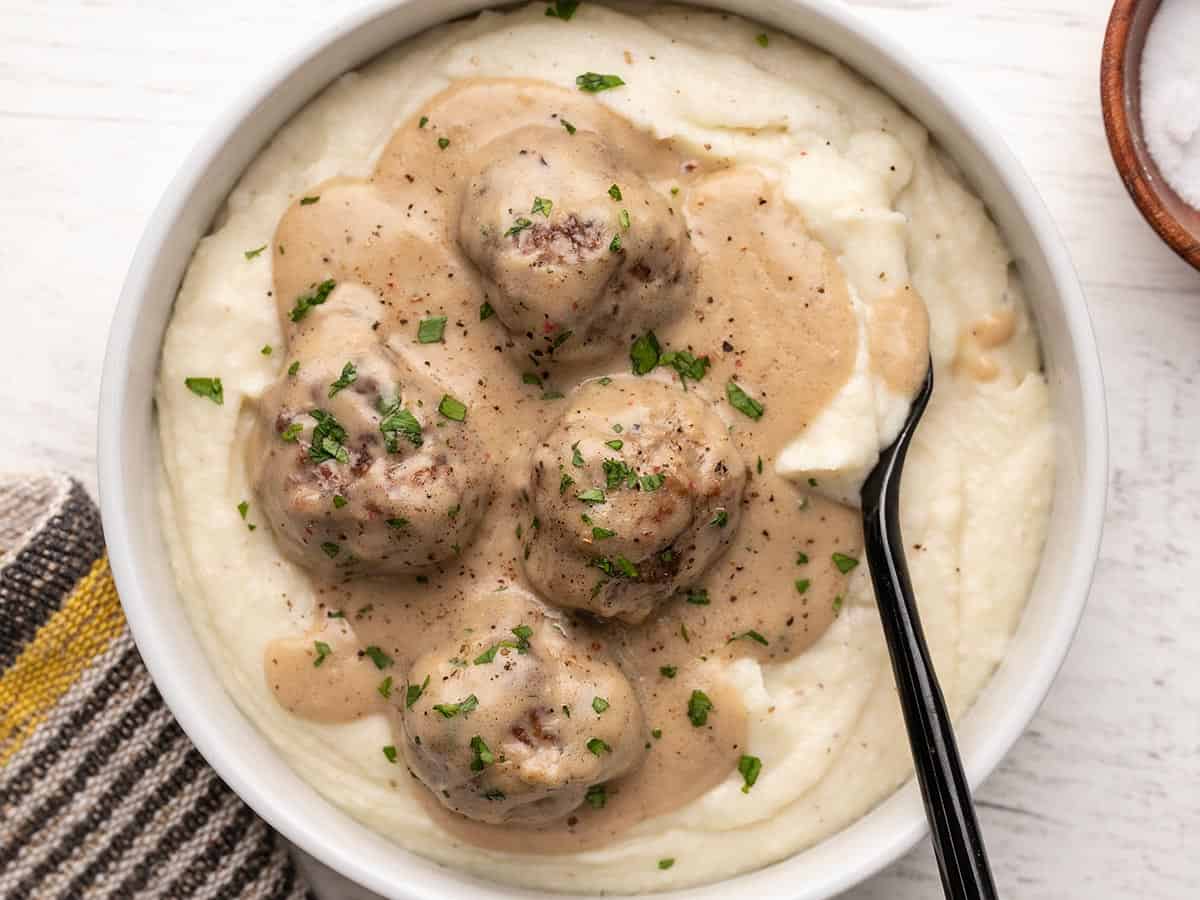 Overhead view of a bowl full of mashed potatoes and Swedish Meatballs.