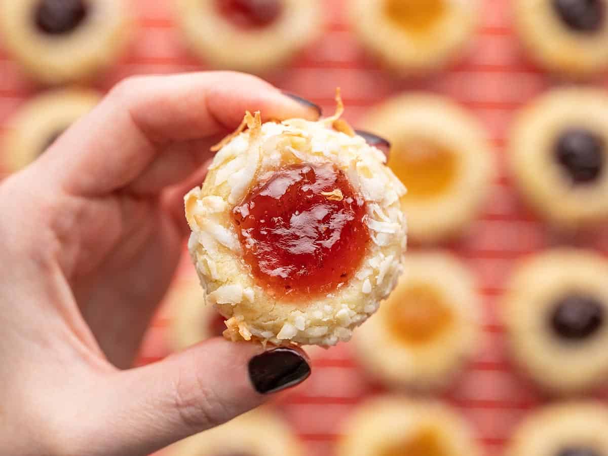 Close up of a jam thumbprint cookie with the rest of the cookies in the background. 