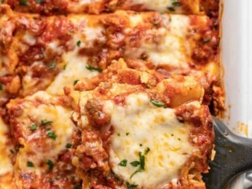 Overhead view of a sliced lasagna with one slice being lifted from the pan.