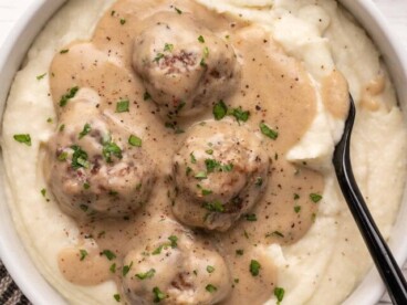 Overhead view of a bowl of mashed potatoes topped with Swedish meatballs.