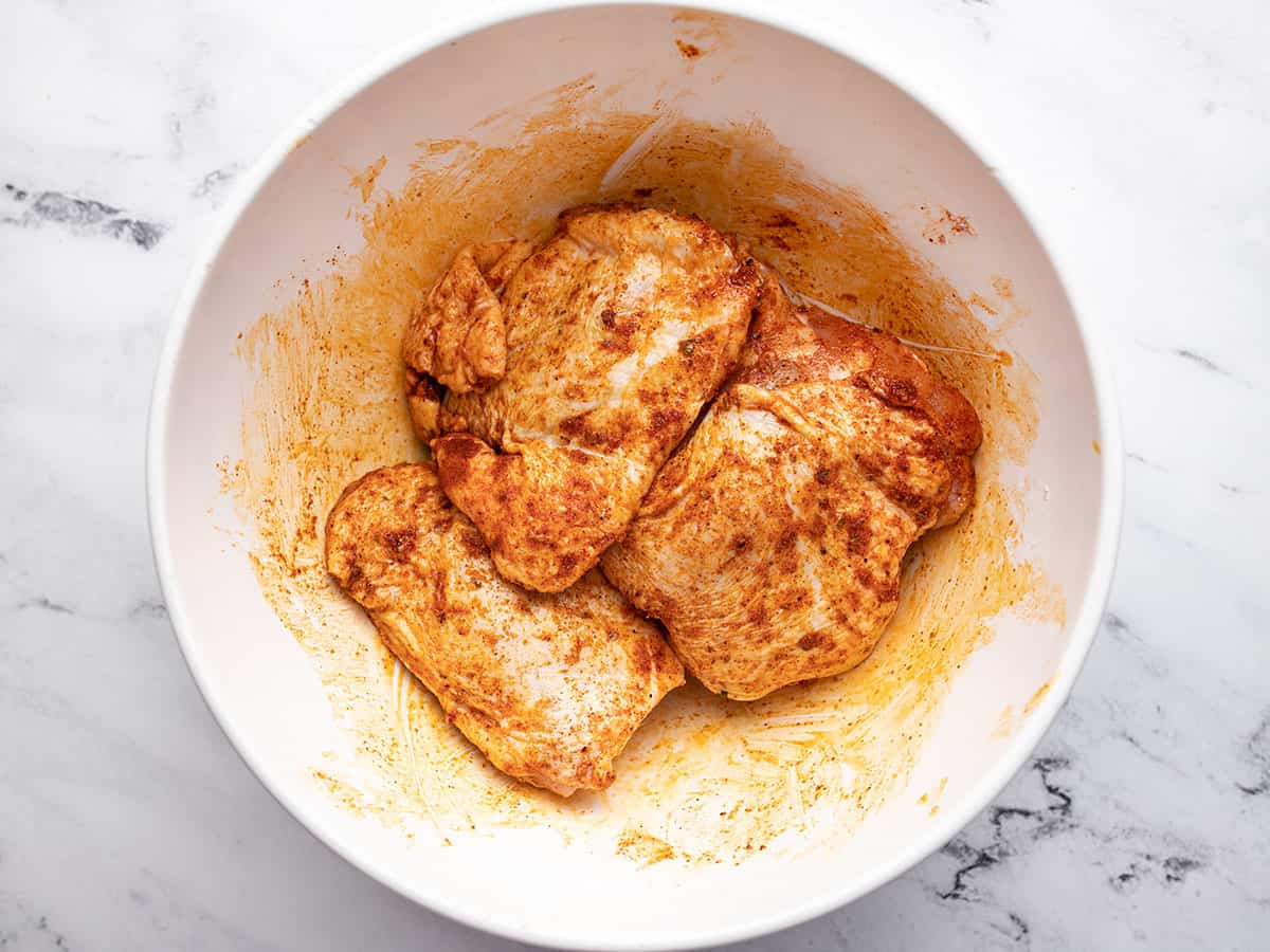 Seasoned chicken thighs in a bowl.