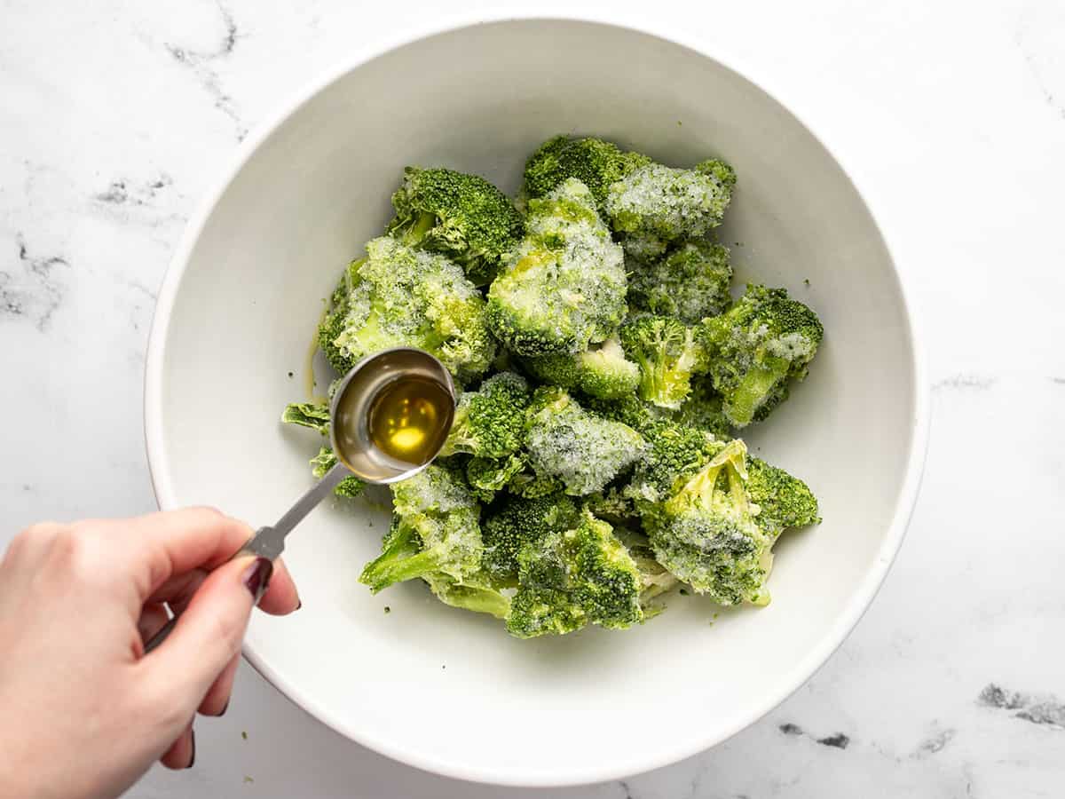 Bir kasede donmuş brokoli, üstüne yağ gezdirilir.