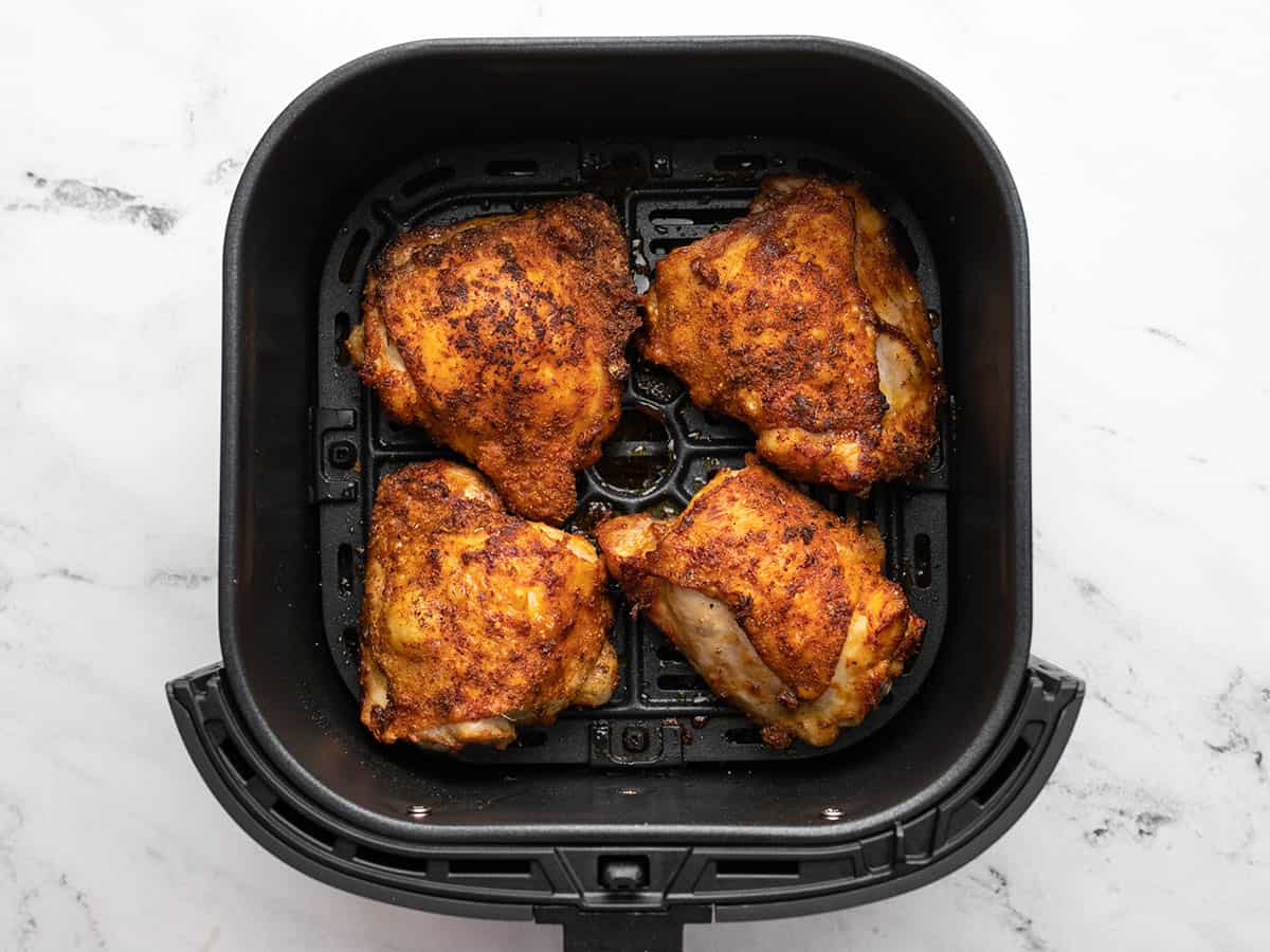 Cooked chicken thighs in the air fryer basket.
