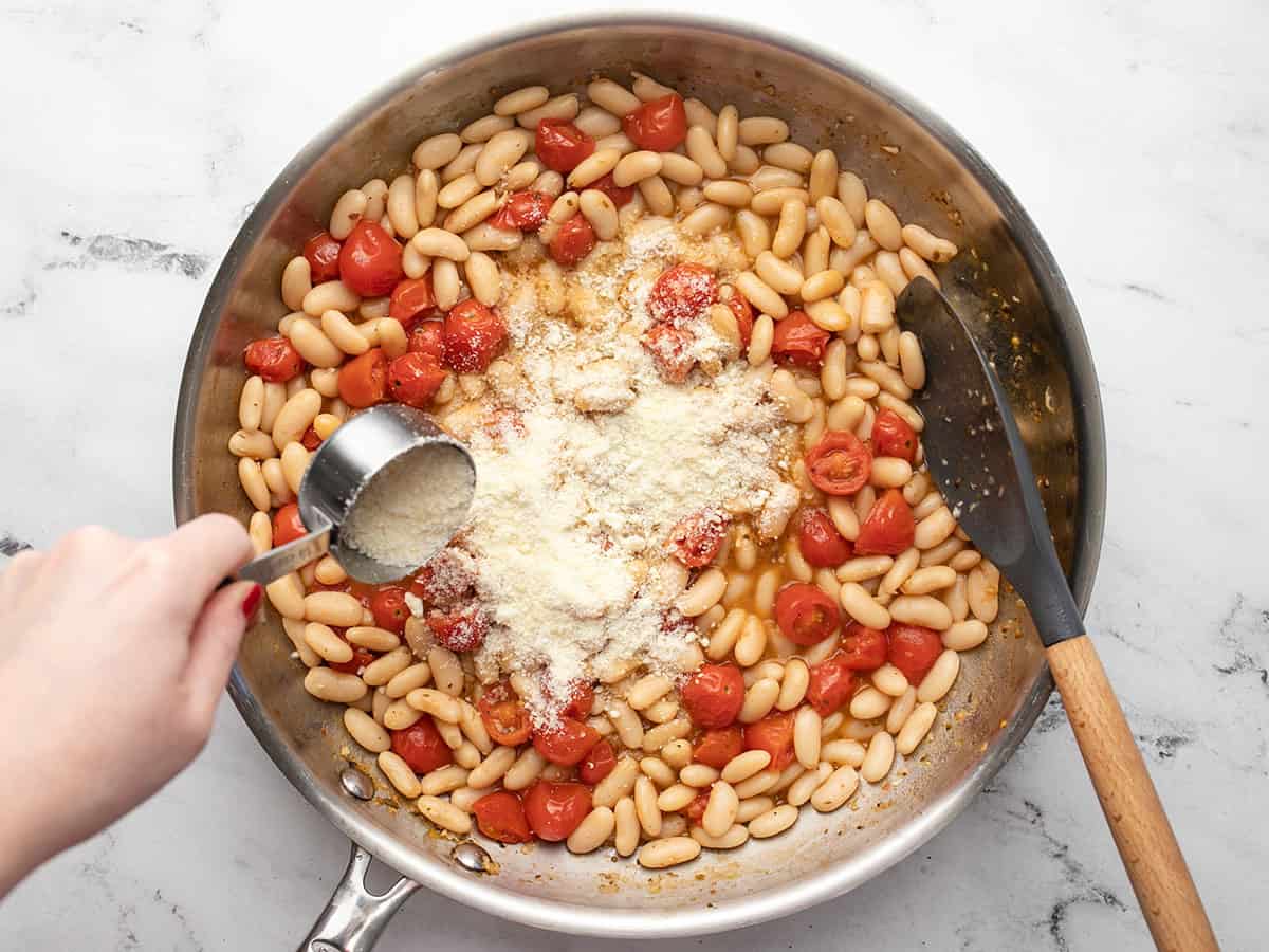 Grated Parmesan being sprinkled into the skillet.