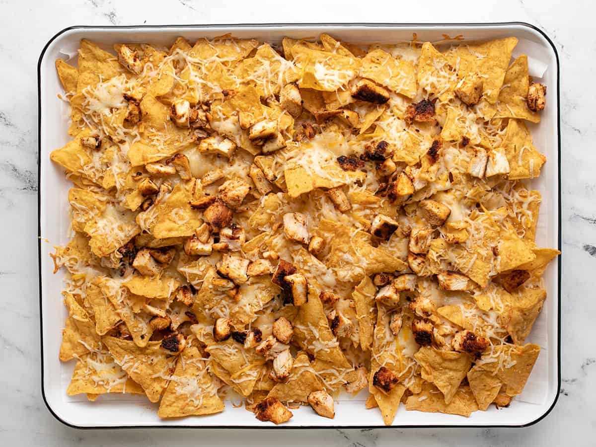 Overhead shot of baked chicken nachos on a sheet pan.