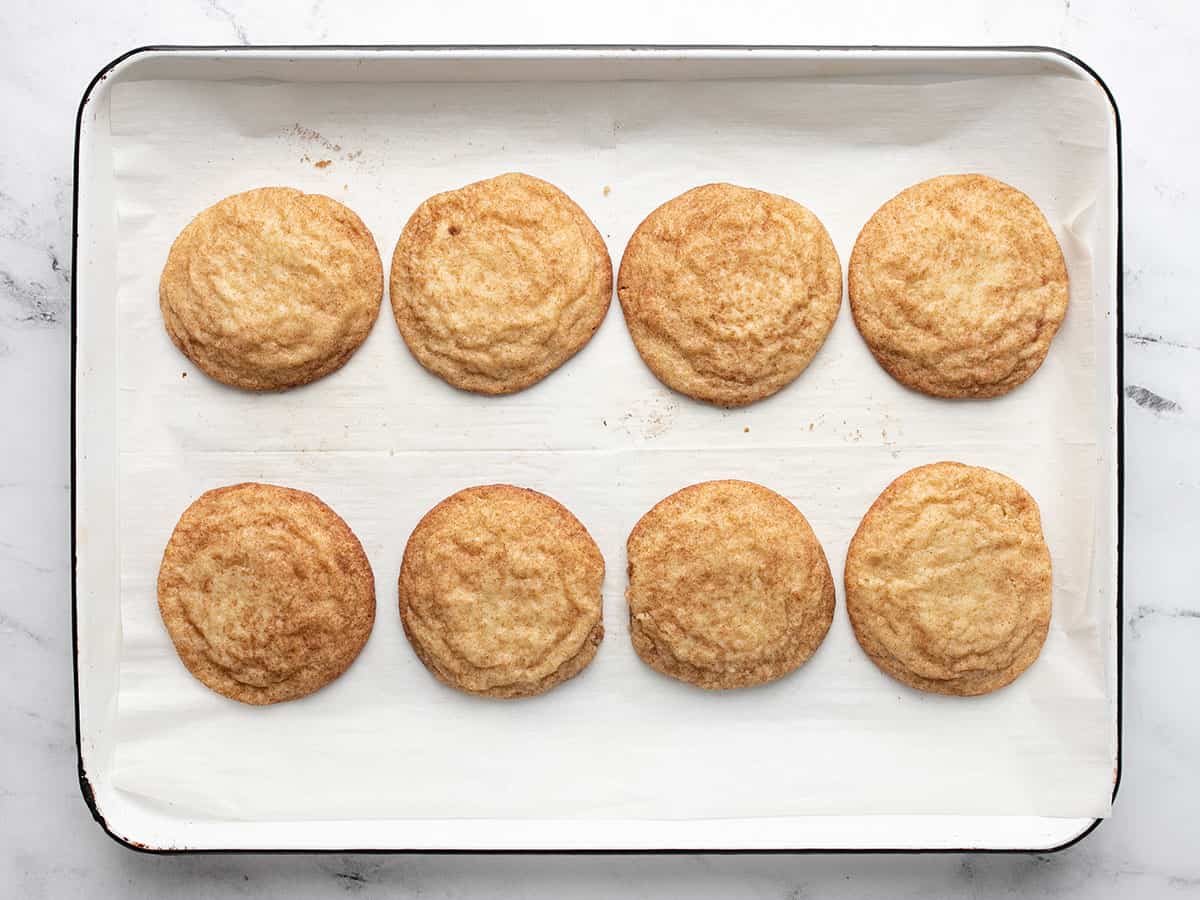 Eight baked snickerdoodles in a sheet pan.