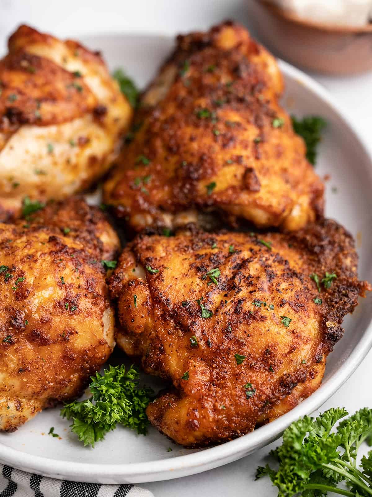 Close up side view of air fryer chicken thighs on a plate.