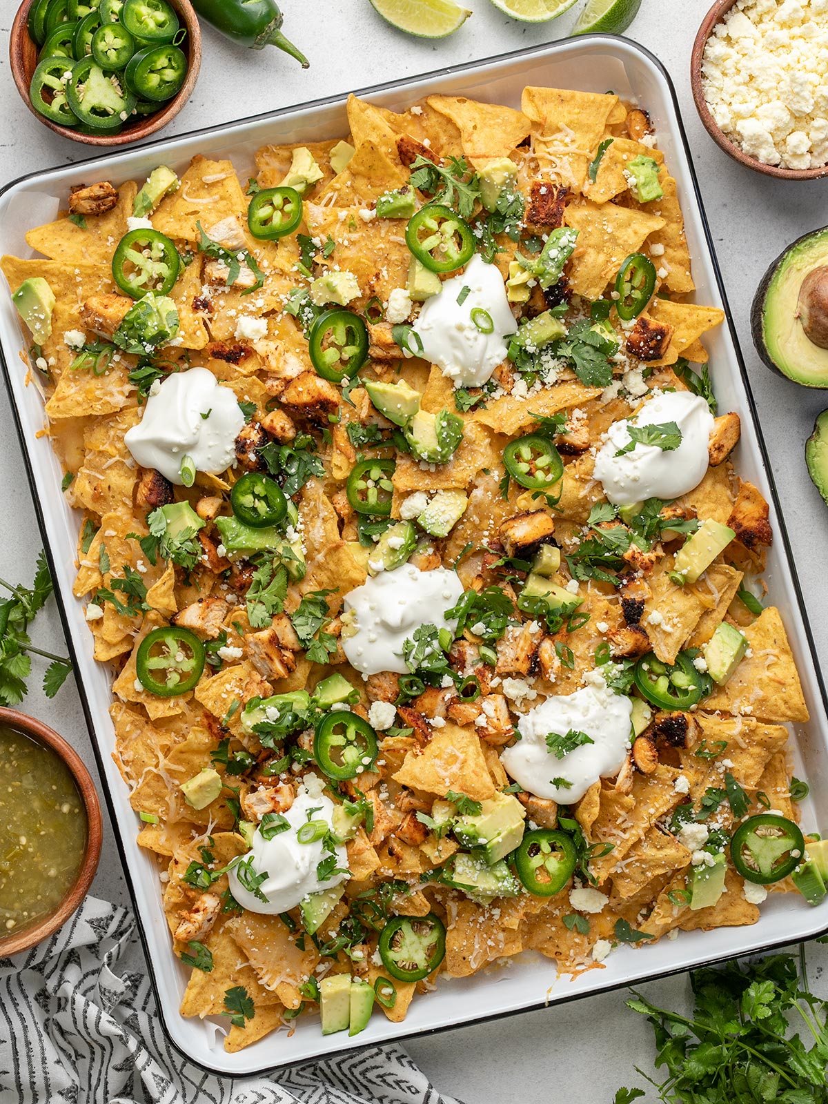 Overhead shot of sheet pan chicken nachos with sliced jalapeño, avocado, and cilantro.