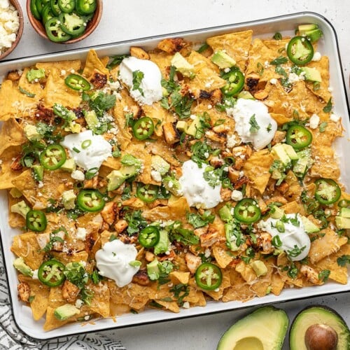 Overhead shot of sheet pan chicken nachos with sliced jalapeño, avocado, and cilantro.