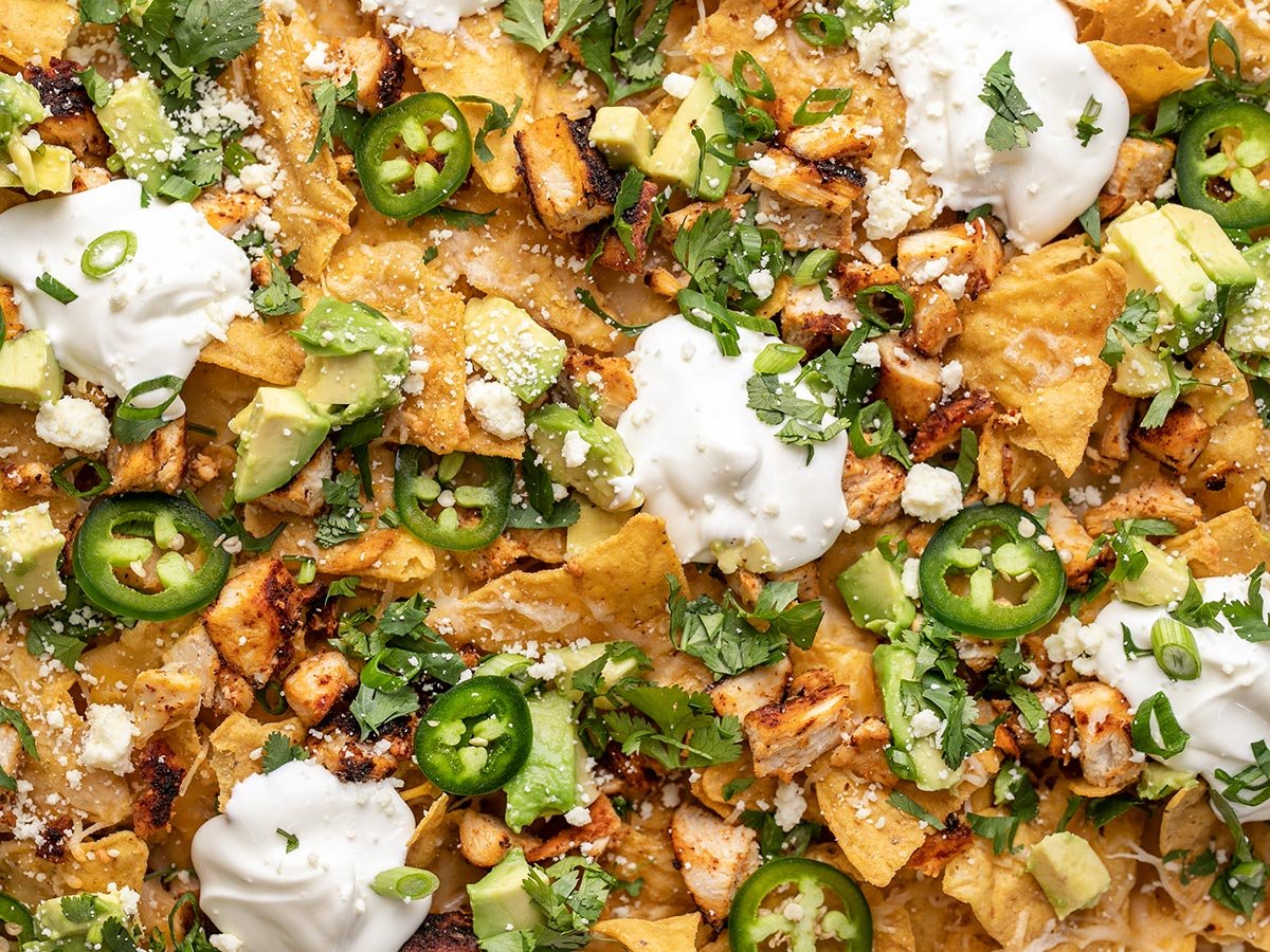 Overhead shot of sheet pan chicken nachos with sliced jalapeño, avocado, and cilantro.