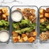 Three glass meal prep containers lined up in a row full of chicken, potatoes, and broccoli.