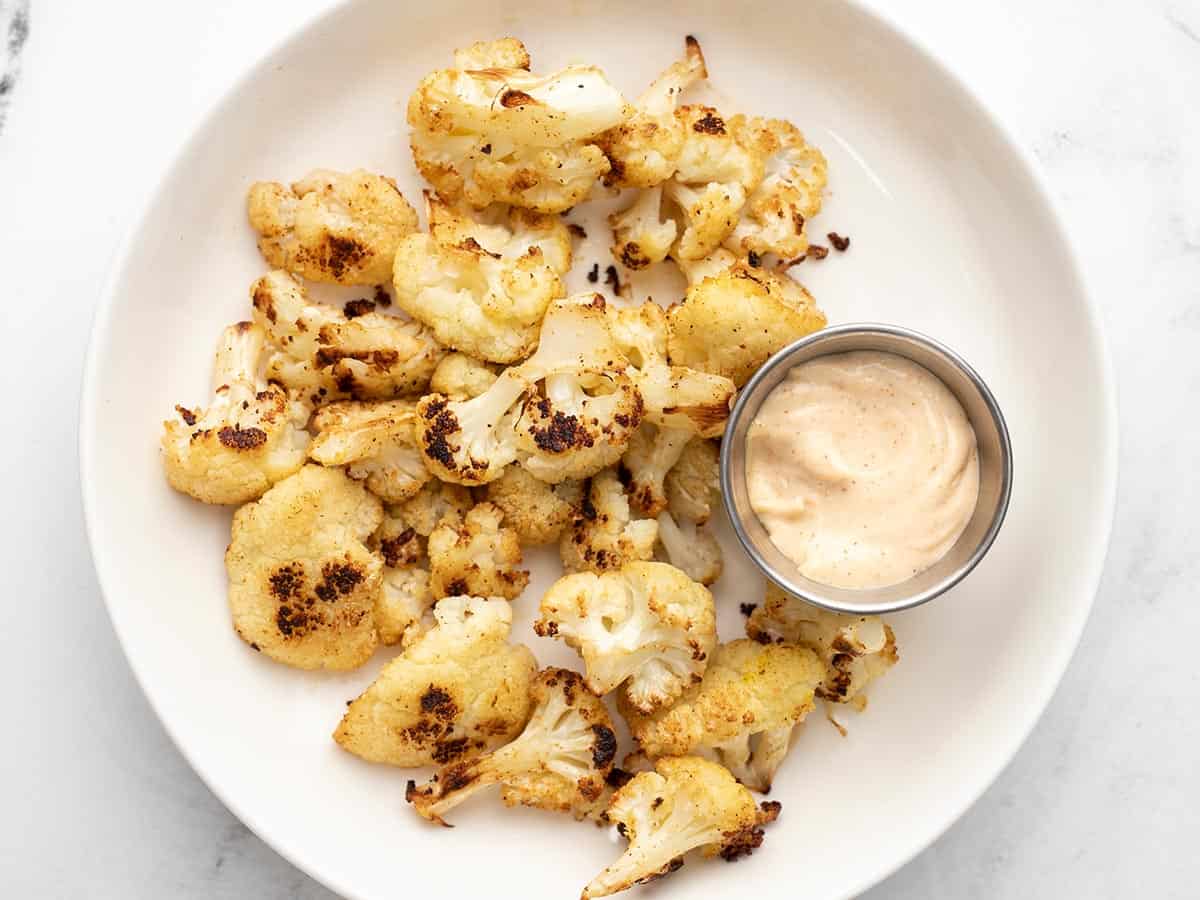 A plate full of Cajun Roasted Cauliflower with dipping sauce. 
